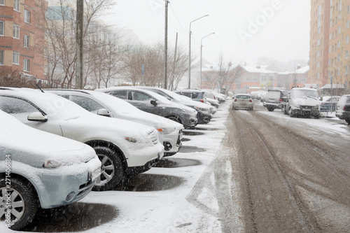 snow-covered cars parked along the road