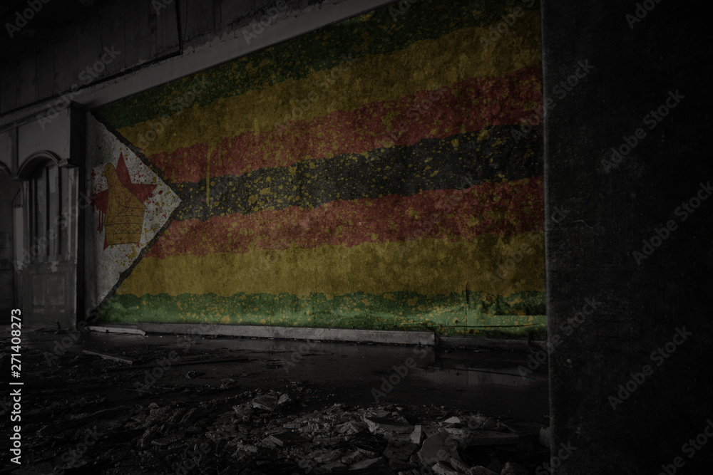 painted flag of zimbabwe on the dirty old wall in an abandoned ruined house.