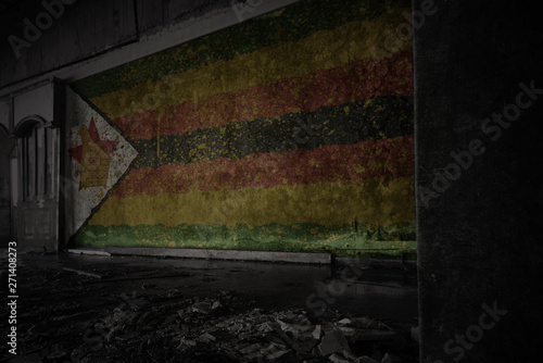 painted flag of zimbabwe on the dirty old wall in an abandoned ruined house.