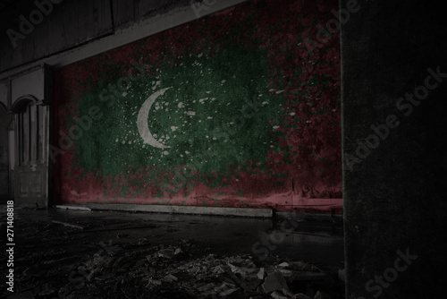 painted flag of maldives on the dirty old wall in an abandoned ruined house.