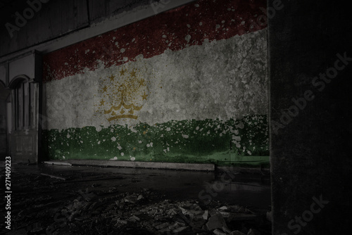 painted flag of tajikistan on the dirty old wall in an abandoned ruined house.