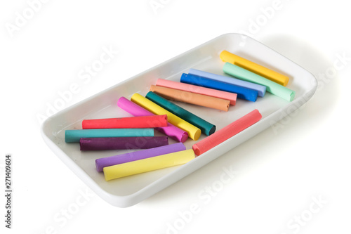 Colored chalk pastels in beautiful white plate isolated on white background
