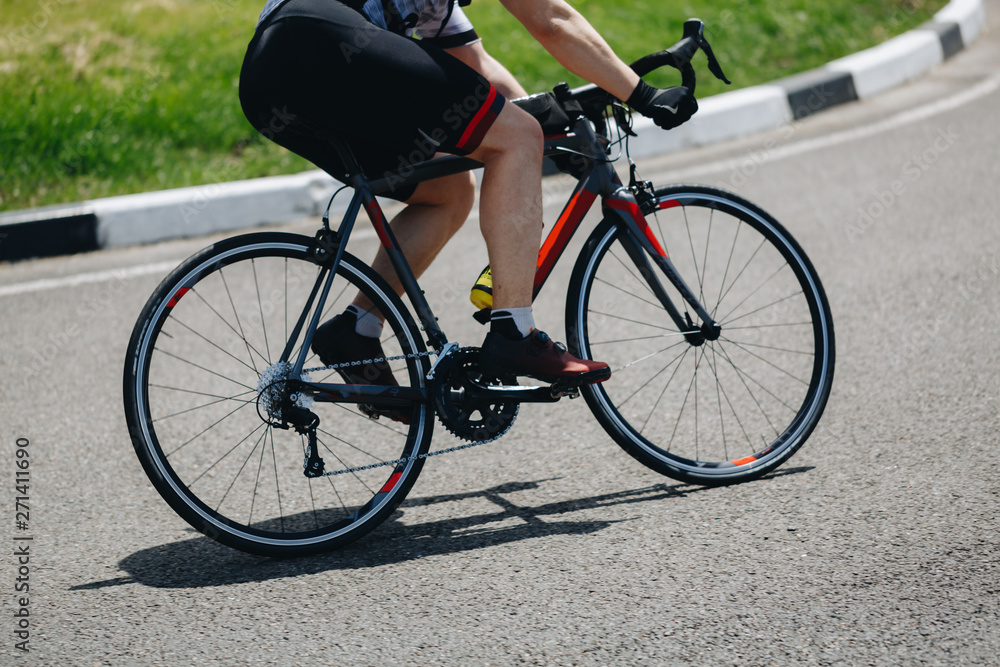 Detail of a road bike with a cyclist pedaling on a road