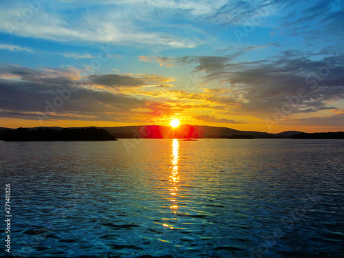 Bright colorful sunset over a lake. Beautiful reflection by a tranquil water of amazing sky and the lakeside at sundown in the summer evening. Lake Elovoe  Spruce Lake   South Ural  Russia.