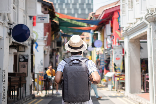 Young man hipster traveling with backpack and hat, happy Asian traveler walking at Haji Lane and Arab street in Singapore. landmark and popular for tourist attractions. Southeast Asia Travel concept