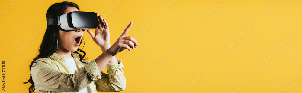 excited girl pointing and using Virtual reality headset, isolated on yellow excited girl pointing and using Virtual reality headset, isolated on yellow