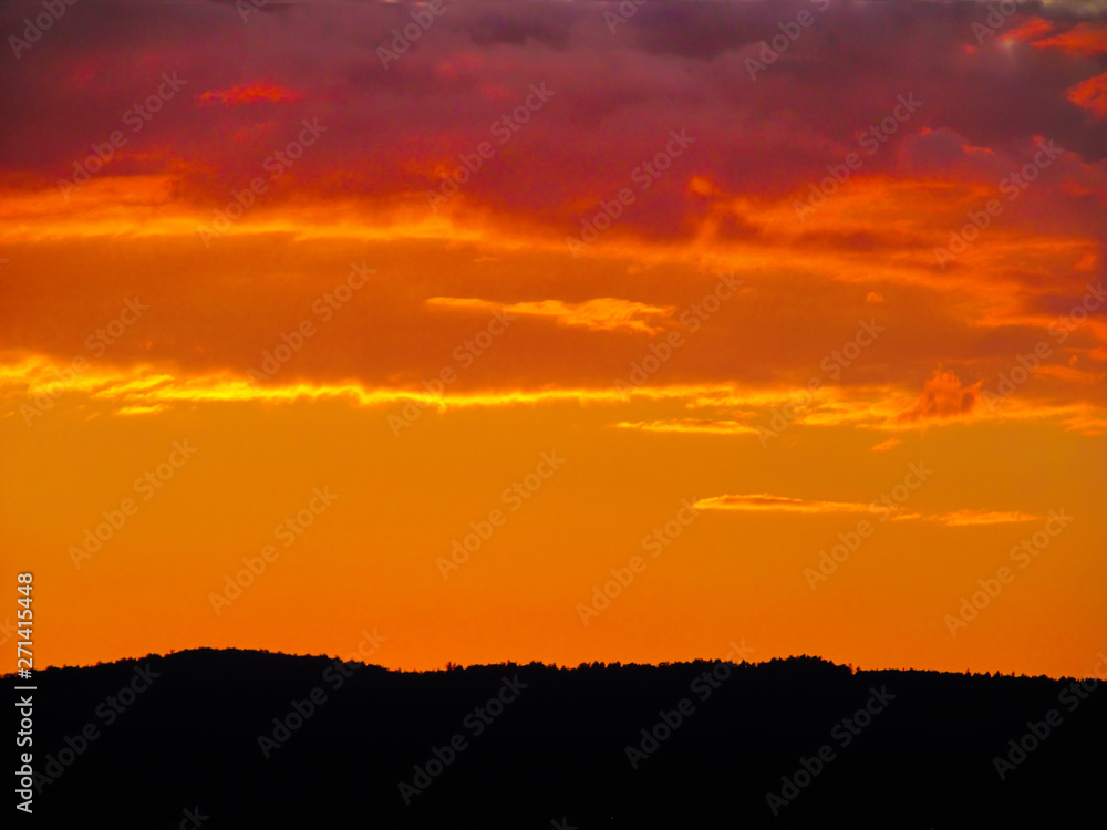 Landscape with sunset and silhouettes of trees. Beautiful view of bright colorful sky happened on evening decline in the summer evening.