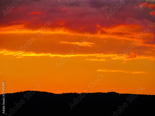 Landscape with sunset and silhouettes of trees. Beautiful view of bright colorful sky happened on evening decline in the summer evening.