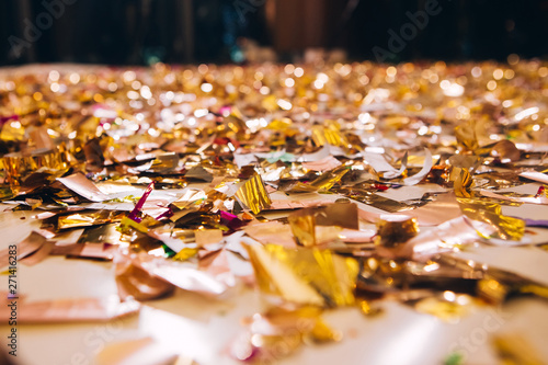 Golden Confetti on a wooden floor reflecting red stage spotlight causing colorful glow