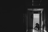 Silhouette of girl sitting alone in the dark,Sad and Serious women sitting hug his knee alone of old condo, Domestic violence, family problems, Stress, violence, with copy space