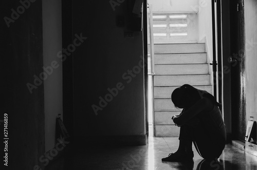 Silhouette of girl sitting alone in the dark Sad and Serious women sitting hug his knee alone of old condo  Domestic violence  family problems  Stress  violence  with copy space