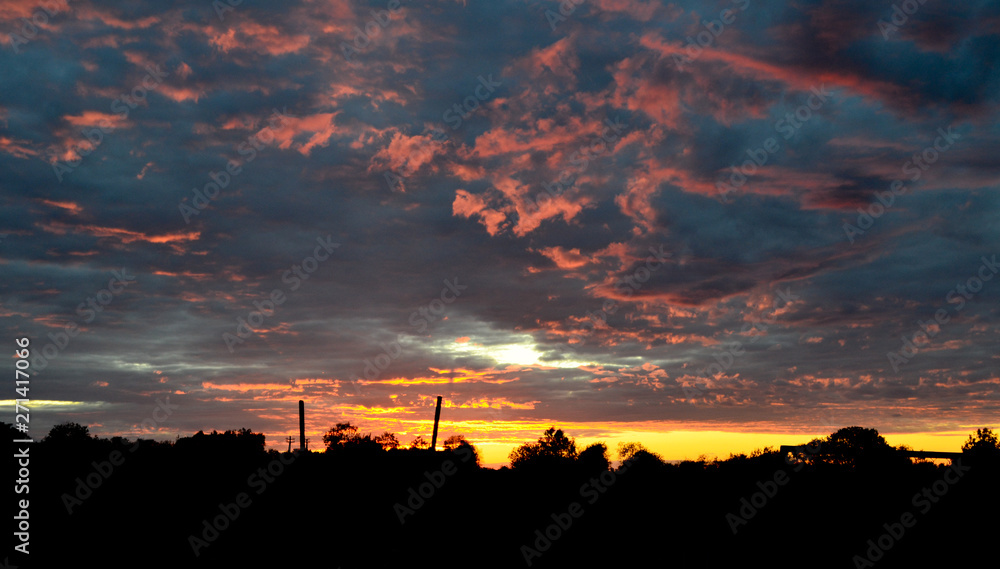 Silhouette of a houses with a gradient blue orange sky during a beautiful sunset in rural village of Russia, Vologda.