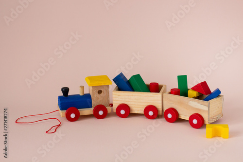 Wooden colorful toy train with details on a soft pink background. Early childhood education, learning to count, preschool and kids game concept