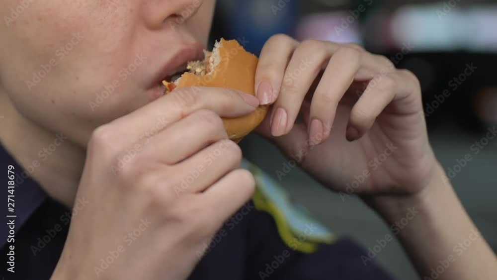 Hungry policewoman eating burger greedily, having lack of time for dinner, duty Hungry policewoman eating burger greedily, having lack of time for dinner, duty