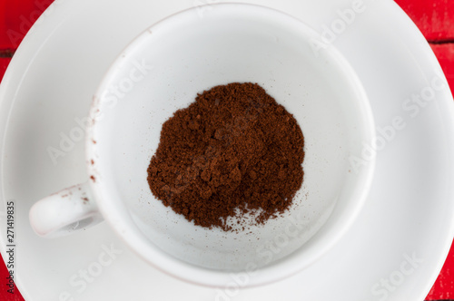 White coffee cup with metal spoon isolated on a red background.