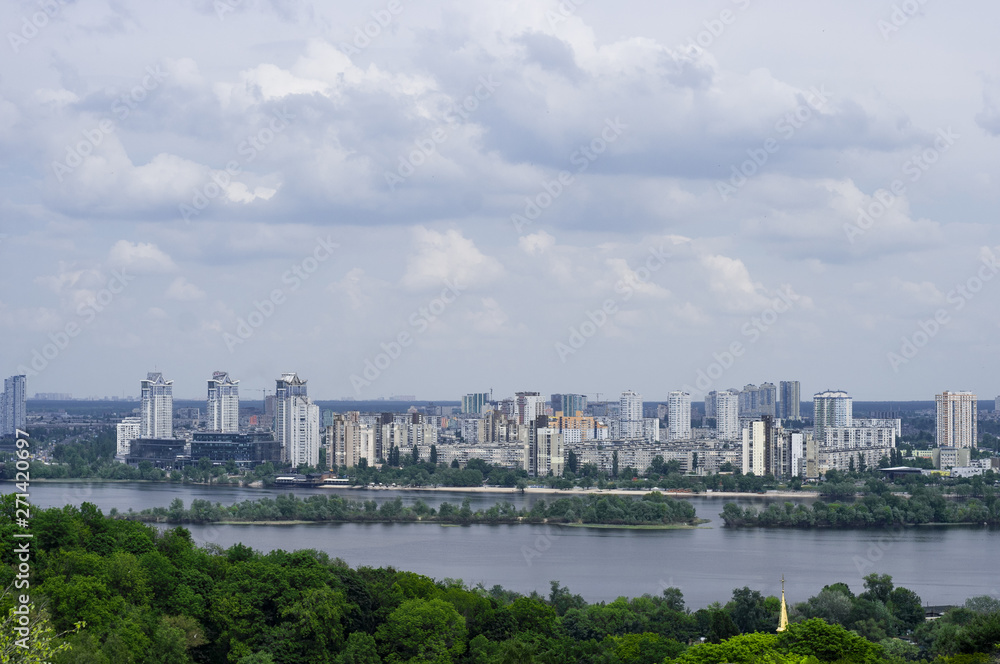 The Dnipro River and the left bank of the city of Kiev under a blue cloudy sky. City landscape of the Ukrainian city