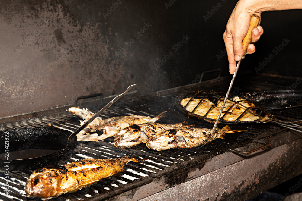 Cocinero asando pescados en la parrila al carbón. Cocinero asando pescados en la parrila al carbón.
