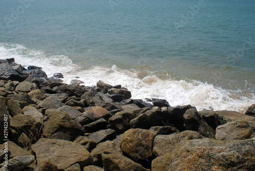 Southern tropical summer ocean coast with rocks and rocks. Lagoon with a yellow sandy beach and azure water.