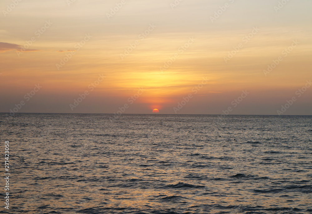 Southern tropical summer ocean coast at sunset. Lagoon with waves in which the sun is reflected.