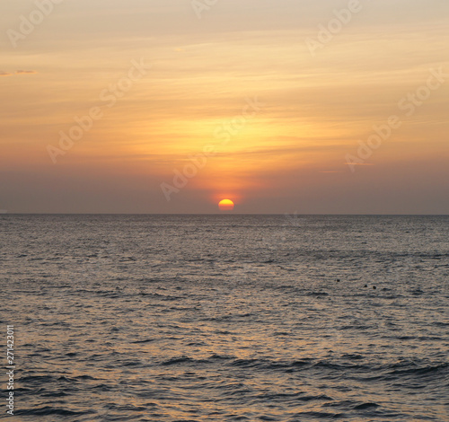 Southern tropical summer ocean coast at sunset. Lagoon with waves in which the sun is reflected.