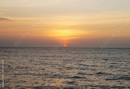 Southern tropical summer ocean coast at sunset. Lagoon with waves in which the sun is reflected.