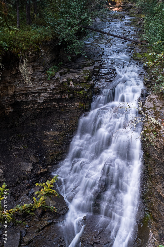 A close up view of a majestic waterfall in Monkman Provincial Park, Canada, the torrent of water squeezes through a gap in rocks and drops, long exposure to create blurred motion to the water, nobody A close up view of a majestic waterfall in Monkman Provincial Park, Canada, the torrent of water squeezes through a gap in rocks and drops, long exposure to create blurred motion to the water, nobody