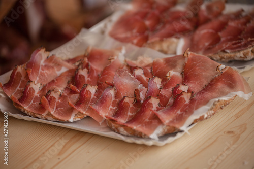 Traditional smoked speck sliced on site during the "Speckfest" celebration in Val di Funes, Dolomites.