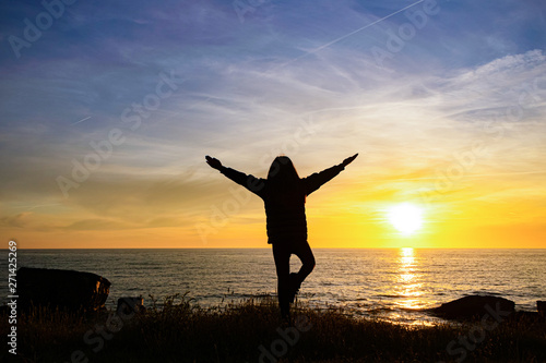 girl silhouette on sunset sea background. girl in the lotus position, yoga.