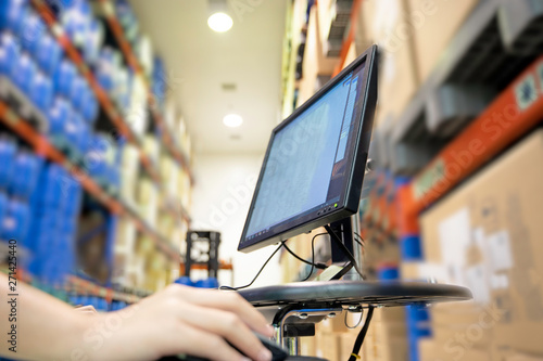 Focus on the computer in the warehouse Blurred background is a stock of many products.