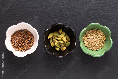 Food concept assortment Oriental spices cardamom pods, coriander seeds, fennel on black slate stone with copy space