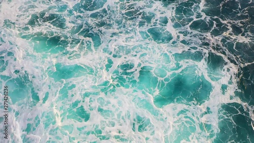 Drone, aerial or top view moving up away ocean blue waves crash coastline cliff drone footage. The water is like marble and crystal clear salt water. Waves break on white sand beach at sunset. Sea