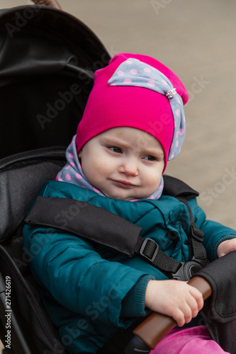Little girl sitting in a baby carriage on the street