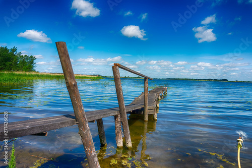 Old rickety wooden jetty leading into a lake