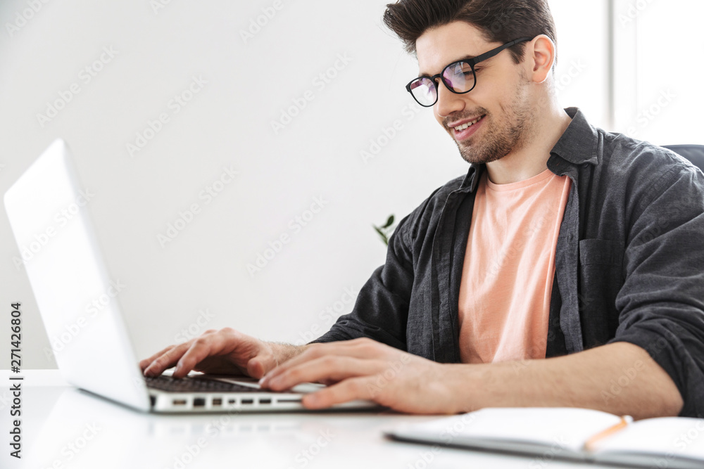 Side view of Smiling man in eyeglasses using laptop computer Side view of Smiling man in eyeglasses using laptop computer