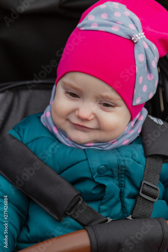 Little girl sitting in a baby carriage on the street