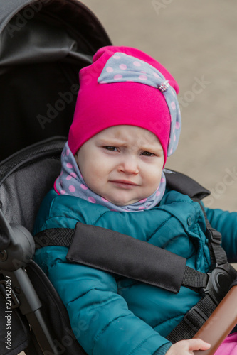 Little girl sitting in a baby carriage on the street