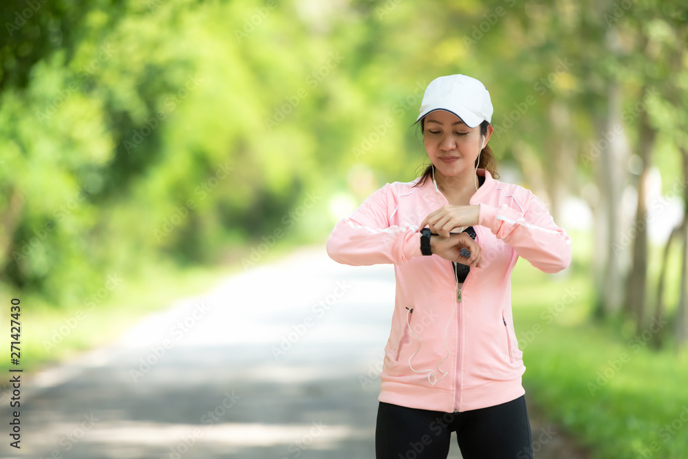Running woman. Sport Women set up watch running before jogging. Outdoor Workout in a Park. Weight Loss and Healthy Concept Running woman. Sport Women set up watch running before jogging. Outdoor Workout in a Park. Weight Loss and Healthy Concept