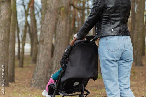 Young mother walks with a baby in a pram.