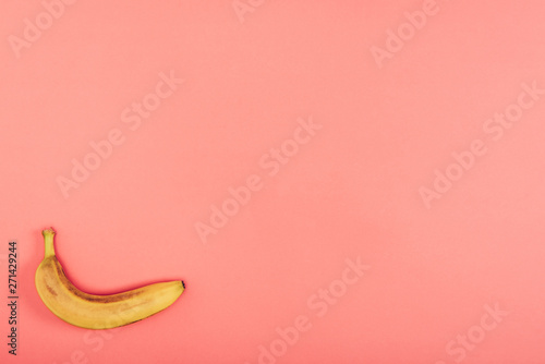 Top view of ripe, bright and yellow banana on colorful coral background with copy space