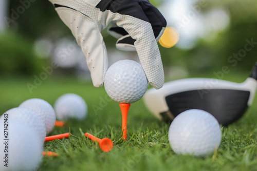 Hand hold golf ball with tee on course, close-up