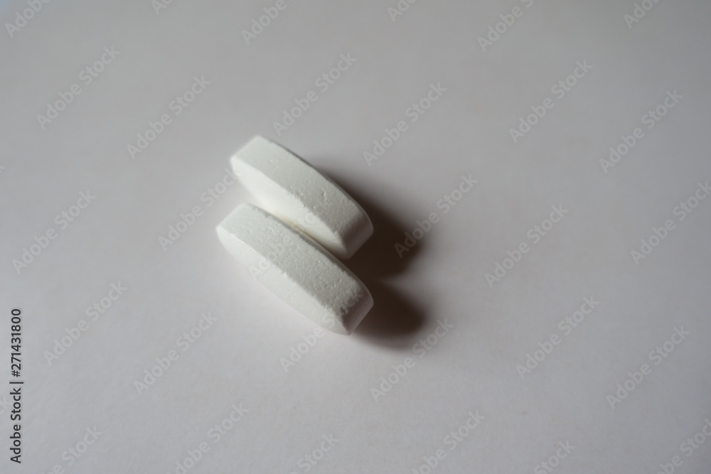 Closeup of 2 big white oblong caplets of calcium citrate Closeup of 2 big white oblong caplets of calcium citrate