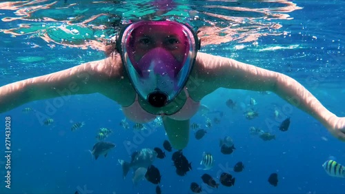 Underwater swimming with tropical fish in Red Sea. Snorkeling girl waving hands to the camera close up photo