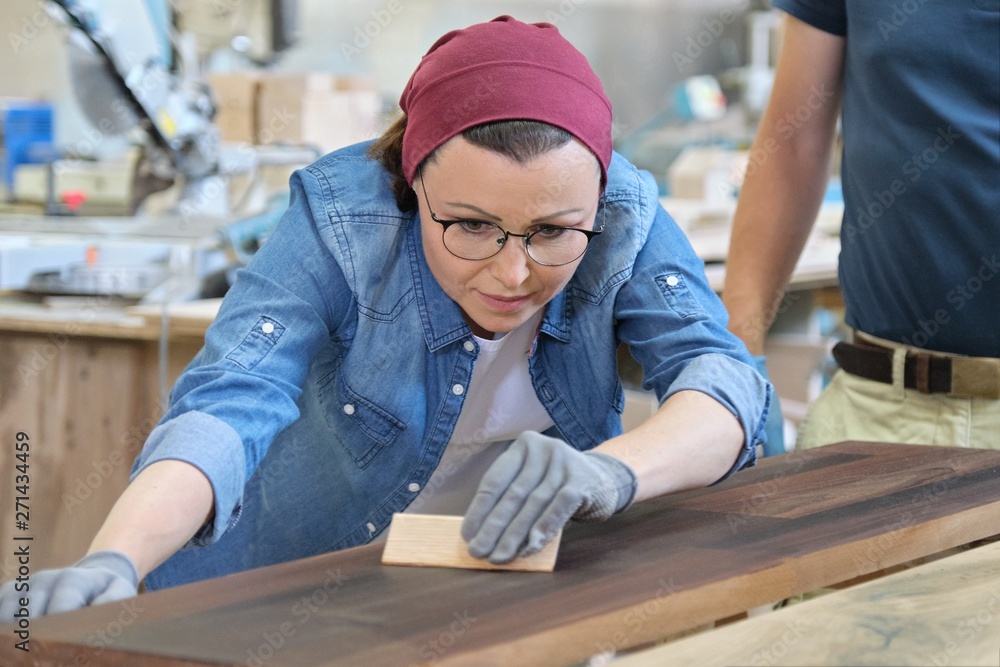 Middle-aged craftswoman working in woodworking workshop. Female varnishing wooden board with oil, varnish. Middle-aged craftswoman working in woodworking workshop. Female varnishing wooden board with oil, varnish.