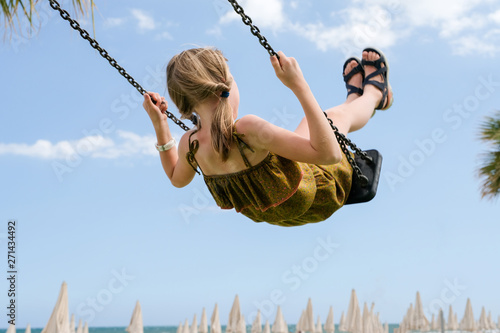 Little girl on a swing against the sky