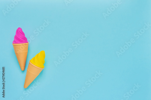 Pink and yellow toy ice-cream on light blue background. Minimalism, summer concept.
