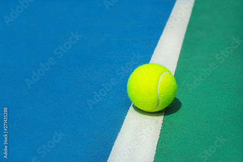 Summer sport concept with tennis ball on white line on hard tennis court. Flat lay, top view, copy space. Blue and green. © IrynaV