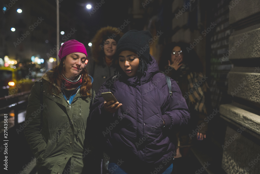 group of young multiracial women walking in the street and looking smartphone
