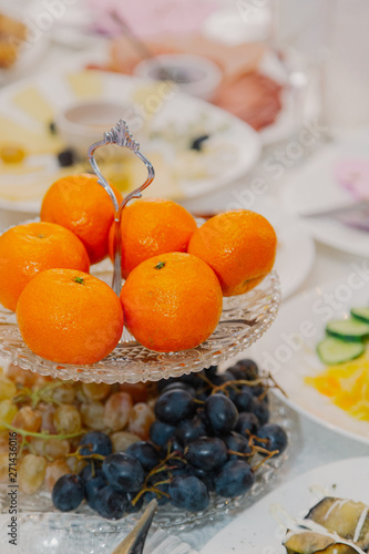 Fresh oranges and grapes on a plate on the festive table.