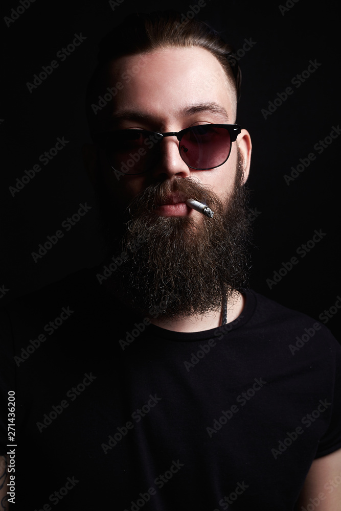 Obraz premium handsome bearded smoking man. Hipster boy
