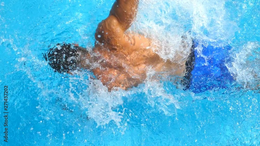 Detail view on sporty guy swimming across pool splashing crystal clear water. Unrecognizable man floating and enjoying recreation on resort in summer sunny day. Concept of vacation. Close up Slow mo Detail view on sporty guy swimming across pool splashing crystal clear water. Unrecognizable man floating and enjoying recreation on resort in summer sunny day. Concept of vacation. Close up Slow mo